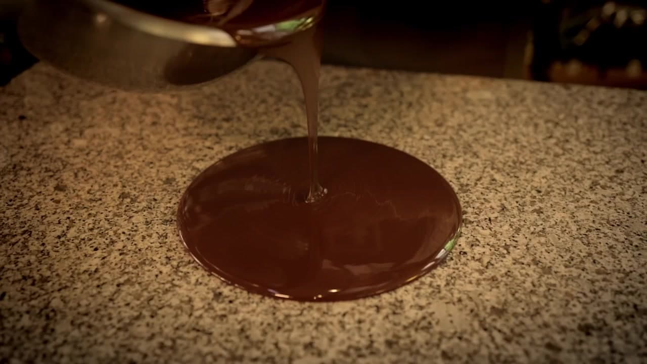 Chocolat fondu versé en ruban sur le marbre de la fonderie briarde pour le tempérage