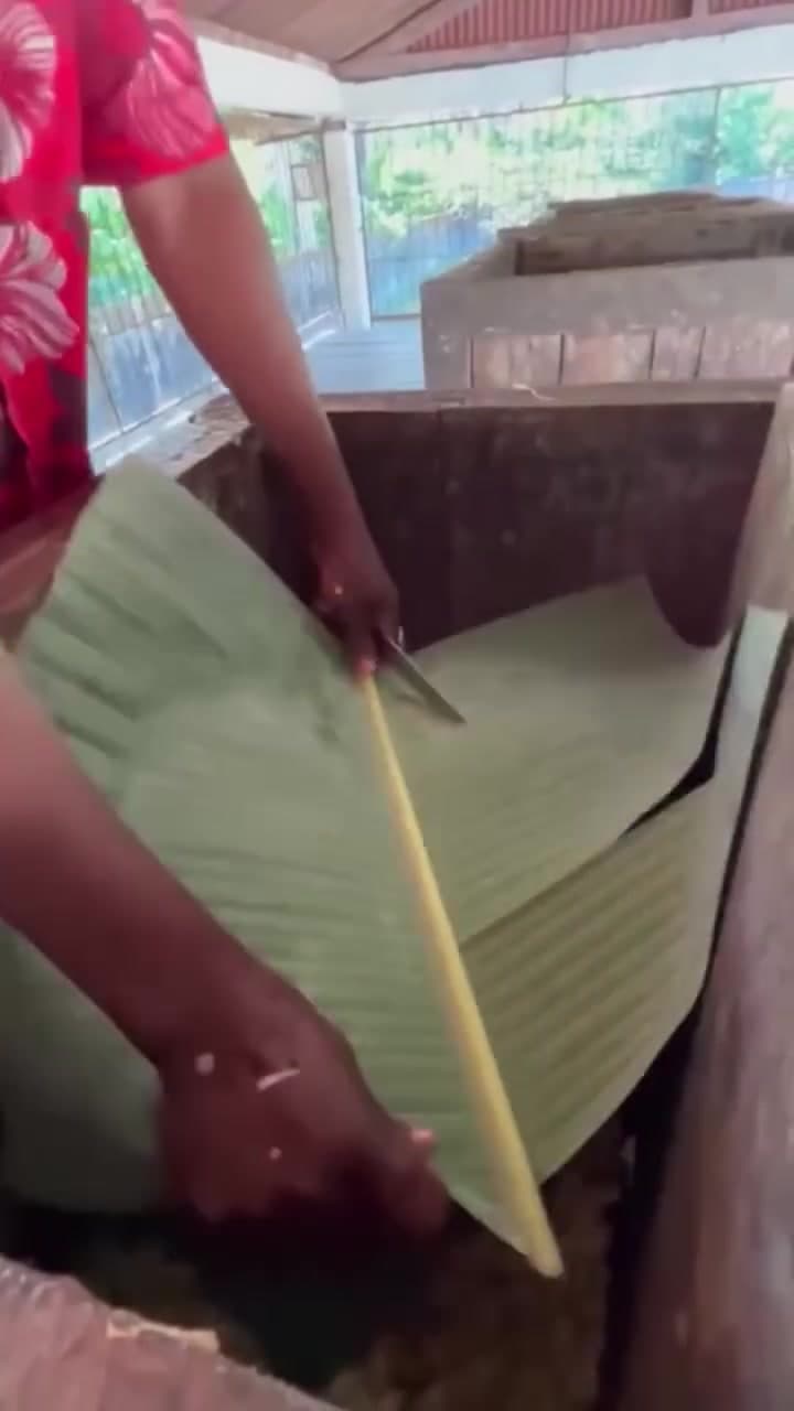 Caisse en bois traditionnelle couverte de feuilles de bananier pour amorcer la fermentation du cacao